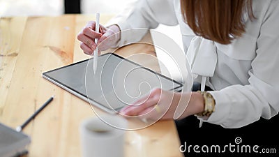 Close up view of freelancer drawing on mock up digital tablet on wooden desk Stock Photo