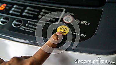 Close up view of finger pushing the start/pause button on the washing machine control panel Editorial Stock Photo