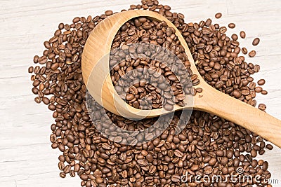 Close up view of full of coffee beans wooden ladle lying on roasted coffee beans Stock Photo