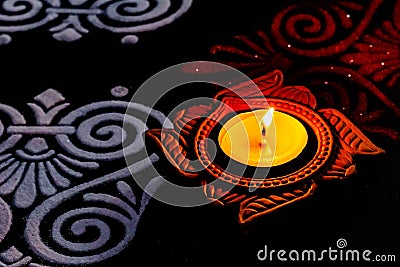 Close up view of glowing diya with white and red rangoli art on black background. diwali cencept Stock Photo