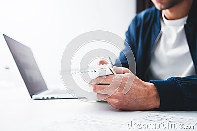 Close up view of hand hold notepad of businessman while working at office and using notebook Stock Photo