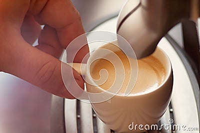 Close up view of the hand of a man working in a coffee house preparing espresso coffee waiting for the coffee machine to finish p Stock Photo