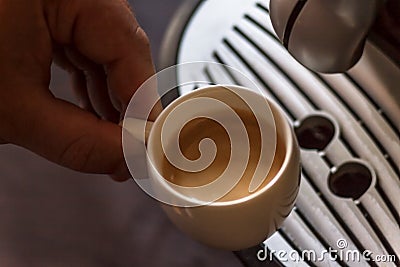 Close up view of the hand of a man working in a coffee house preparing espresso coffee waiting for the coffee machine to finish p Stock Photo