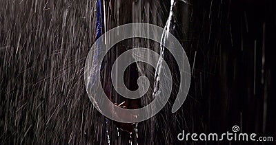 Close-up view of hand of muscular man standing under heavy rain in dark night Stock Photo