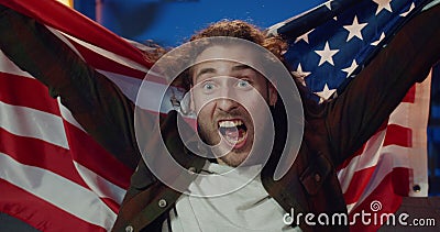 Close up view of handsome young man sitting in front of tv and supporting favourite team. Long haired guy with USA flaf Stock Photo