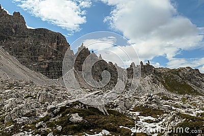 A close up view on high and sharp peaks of Dolomites in Italy. The sky is full of soft clouds. Lots of lose stones and pebbles. Stock Photo