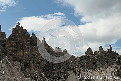 A close up view on high and sharp peaks of Dolomites in Italy. The sky is full of soft clouds. Lots of lose stones and pebbles. Stock Photo