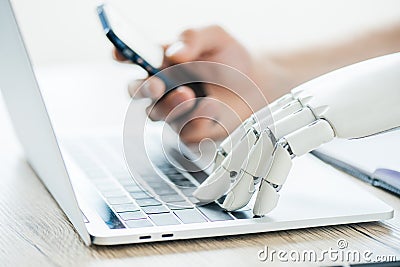 close-up view of human and robot hands using smartphone and laptop Stock Photo