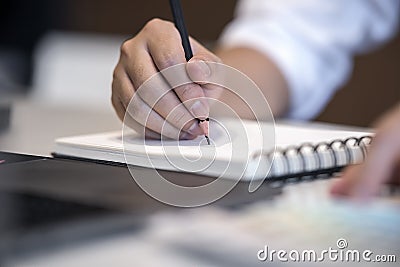 Close up view image of man writing on notebook while working Stock Photo