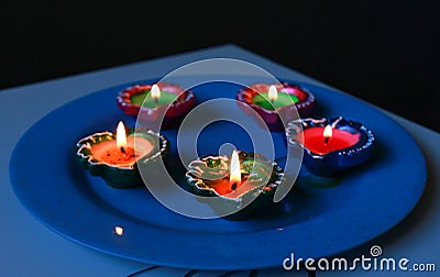 A close-up view of lit diyas arranged on plate Stock Photo