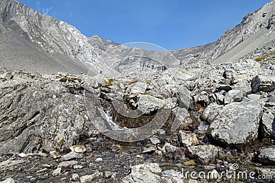 A close up view looking up at falling water from a creek rolling down the side of a steep mountain with the mountain Stock Photo