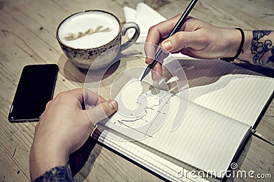 Close-up view of male hands with note book and coffee draw diagramms Stock Photo