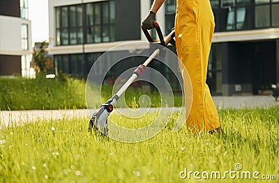 Close up view. Man cut the grass with lawn mover outdoors in the yard Stock Photo