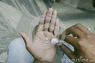 Close-up view of man hand pouring homeopathic pills from the bottle on hand. Top view image of male hands taking daily dose of Stock Photo