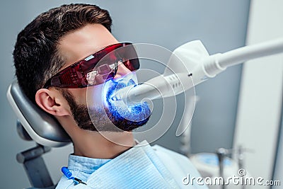 Close up view of man undergoing laser tooth whitening treatment to remove stains and discoloration Stock Photo