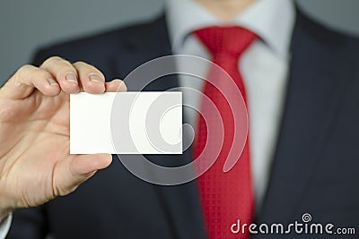 Close-up view of a manager`s hand in a suit and with a red tie holding an empty business card Stock Photo