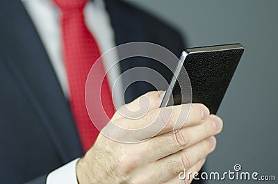 A close-up view of a manager`s hand in a suit and with a red tie using a smartphone Stock Photo