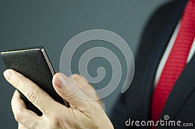 Close-up view of manager in suit with red tie holding smartphone with leather Stock Photo