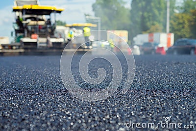 Close up view on the new asphalt road on which special equipment is working. Blurred photo of construction site. Stock Photo