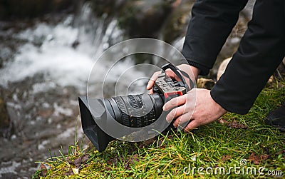 Close up view of a photo video mirrorless camera held in hand by a male photographer in nature landscape Stock Photo