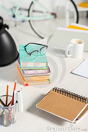 close up view of piles of books, notebooks, folders, cup of coffee and eyeglasses at workplace Stock Photo