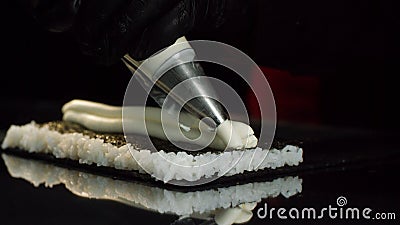 Close-up view of process of preparing roll sushi. Chef in gloves imposes from pastry bag of cream filling on sheet of Stock Photo