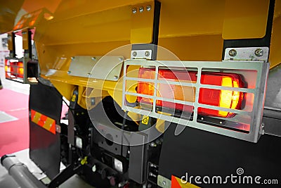 Close up view on rear car tipper truck red and yellow light with silver metal protective cover housing. Commercial transport indus Stock Photo
