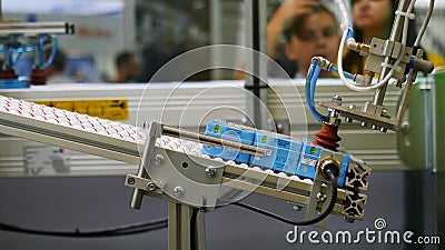 Close-up view of robotic machine sorting the juice boxing at the robotics forum exhibition and blurred figures of Editorial Stock Photo