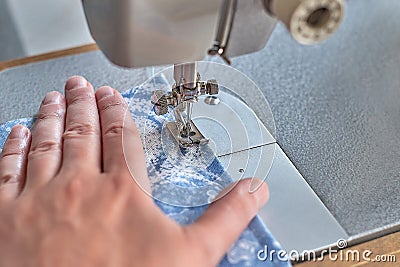 Close up view of sewing process. Female hands stitching blue fabric Stock Photo