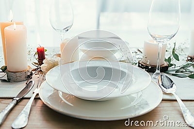 close up view of stylish table setting with candles, empty wineglasses and plates Stock Photo