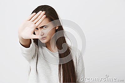 Close up view of teenage girl with dark long hair making stop gesture with hand, frowning face. Cropped isolated Stock Photo