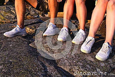 Close up view of three pairs of legs in white sneakers in nature at sunset Stock Photo