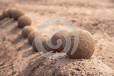 Close up view of an undulating sand castle hill or wall with perfectly smooth round balls or spheres of wet sand placed on the Stock Photo