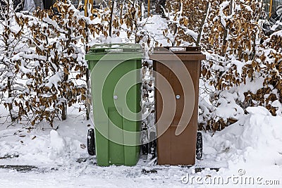 Close up view of waste and recycling containers on snowy bushes background. Stock Photo