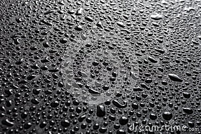 Close-up view of water drops on black hydrophobic surface macro sith selective cous and background blur Stock Photo