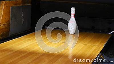 Close-up view of white pins standing in th end of bowling alley lane and rolling bowling ball in a sport club. Media Stock Photo