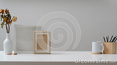 Close up view of workspace with mock up frames, coffee cup, pencils and decorations on white wooden table Stock Photo