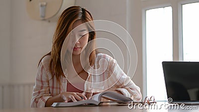 Close up view of college girl concentrating on her assignment with book Stock Photo