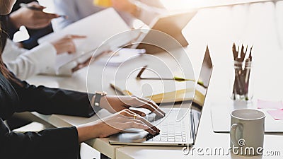 Close up view of business typing on laptop while siting in meeting room with co worker and office supplies Stock Photo