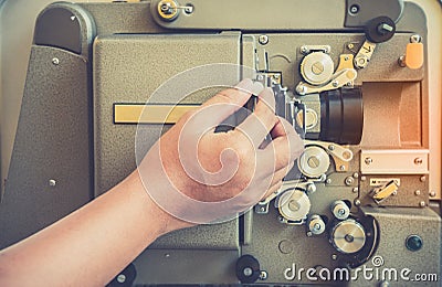 Close up of vintage classic mobile 8mm or 16mm movie film projector with hand and vintage color style. Stock Photo