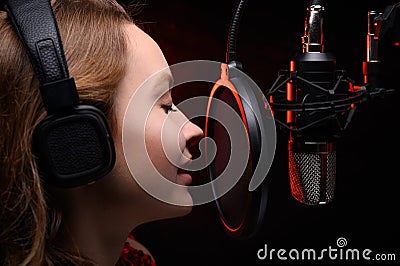 Close-up Vocalist working in the studio with a studio microphone in headphones. Against a dark background, with red smoke. Effect Stock Photo