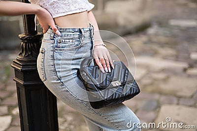a close-up of the waist of a girl in fashionable clothes and a handbag in her hands Stock Photo