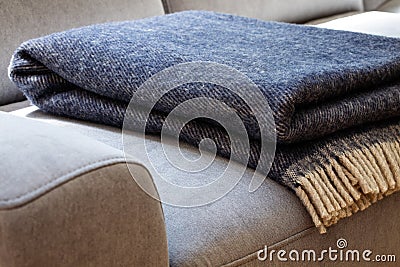 Close-up of a warm, navy blue, wool blanket with beige fringe on a comfy, gray sofa in a cozy living room interior Stock Photo