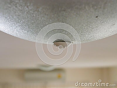 Close up of water leakage dropping through a ceiling lamp at home - problem of water leaking in a house Stock Photo