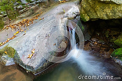 Close-up of the waterfall movement. The stream of water flows around the rock and falls down. Long exposure shot Stock Photo