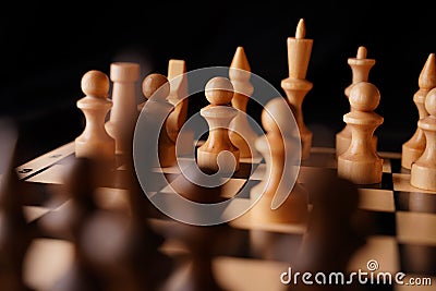 Close up of white and black chess pieces on board. Selective focus on first move of white pawn on chessboard. Concept of Stock Photo