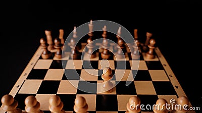 Close up of white and black chess pieces on board. Selective focus on first move of white pawn on chessboard. Concept of Stock Photo