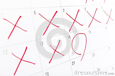 Close up of a white calendar page with some the days crossed off red X Stock Photo