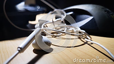 Close up white Earphone on wooden table with light and shadow. home music relax concept Stock Photo
