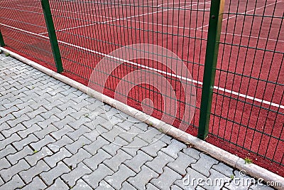 Close-up of white marking lines of outdoor basketball court fenced with protective metal fence Stock Photo